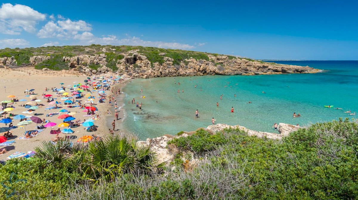 The sheltered cove of Calamosche with clear water between two rocky headlands