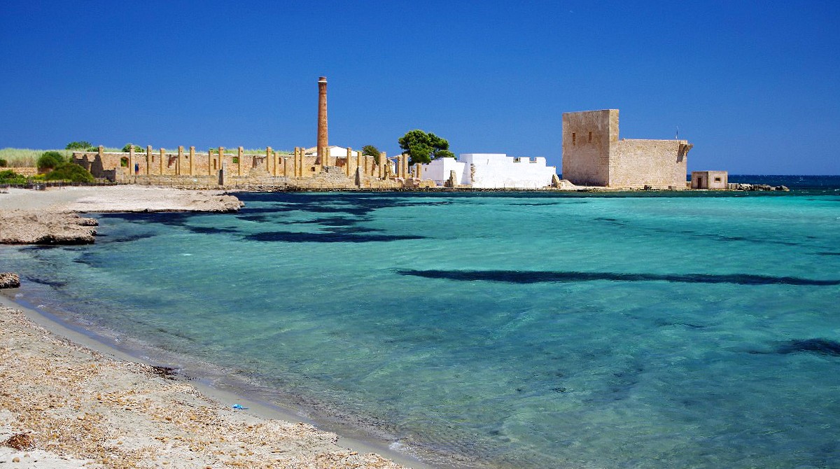 The Tonnara ruins and Swabian Tower rising behind the sandy beach of Vendicari
